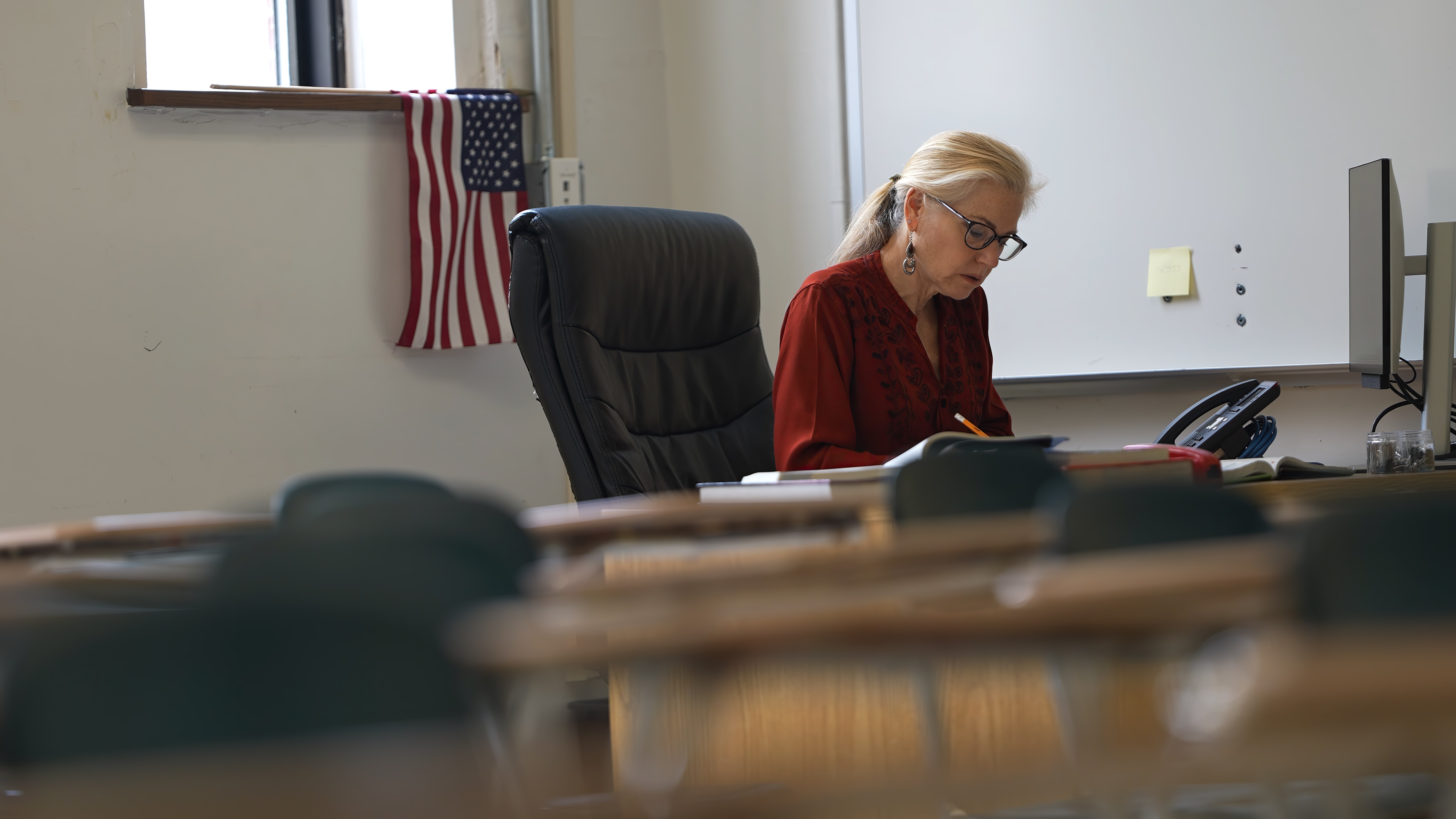 A district administrator working at her desk, an American flag beside her.